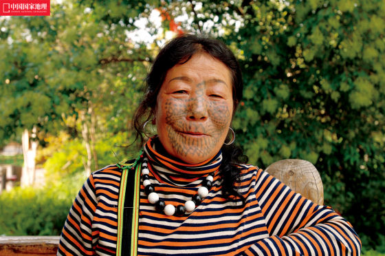 出生于1957年的董春莲是独龙族里最年轻的文面女,2007年5月至今,她和包括自己小儿子在内的8个独龙族同胞一起,在位于昆明市的独龙族村寨中向游客展示独龙族文化。一位民族村工作人员说,当时到独龙江峡谷地区找董春莲花了3天时间,开去的吉普车轮胎也被地上尖锐的石子划坏了3个。摄影/李旭 出生于1957年的董春莲是独龙族里最年轻的文面女,2007年5月至今,她和包括自己小儿子在内的8个独龙族同胞一起,在位于昆明市的独龙族村寨中向游客展示独龙族文化。一位民族村工作人员说,当时到独龙江峡谷地区找董春莲花了3天时间,开去的吉普车轮胎也被地上尖锐的石子划坏了3个。摄影/李旭