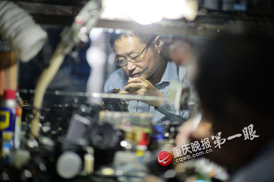 灯光下,陈亚军为顾客精心修理老式的胶片相机。图片来源:重庆晚报第一眼 灯光下,陈亚军为顾客精心修理老式的胶片相机。图片来源:重庆晚报第一眼