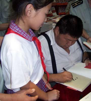 毛新宇在给民工子弟学校的学生签名