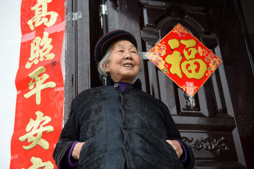 资料图片：在广西环江毛南族自治县大安乡可爱新村，一名老人站在新居家门口（2015年3月11日摄）。自2014年7月1日起，广西将城乡居民基本养老保险基础养老金最低标准由原来每人每月75元提高至90元。 新华社记者 陆波岸 摄