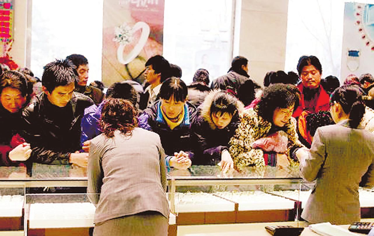 顾客在北京菜百商场柜台前购买黄金饰品_财经