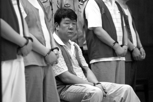 刘振江的腿被摔折,只能坐着受审.本报记者 王俭 摄