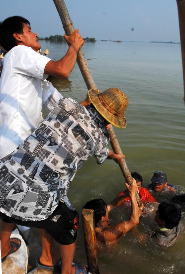 图文:抢险人员用沙包和木桩加固堤坝