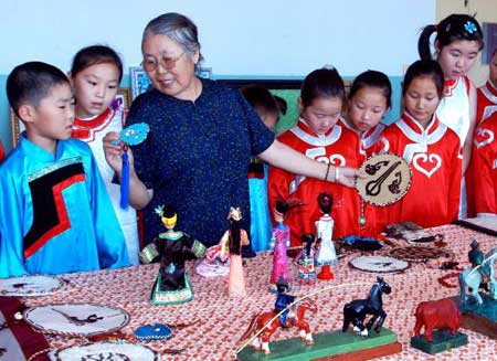 图文:老人为儿童讲解民族传统手工艺品制作