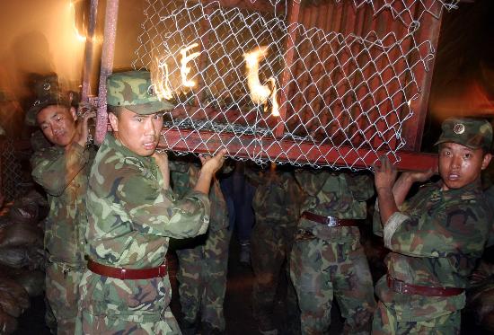 图文:官兵抬着填装沙袋用的铁笼投入堵口战斗
