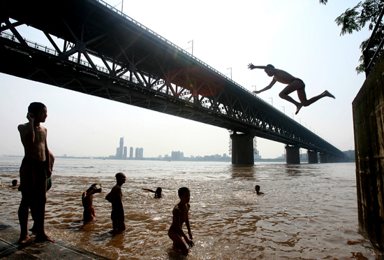 图文:一群男孩子在江边跳水游泳