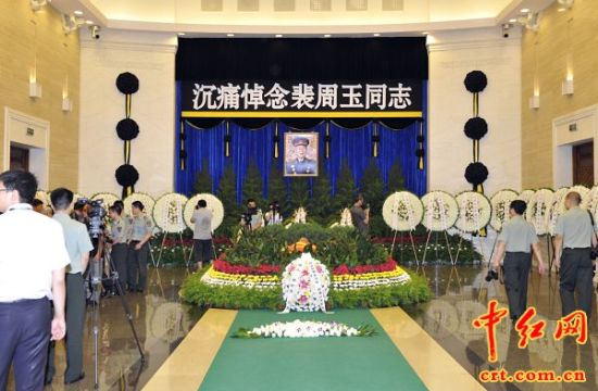 今天上午,八宝山革命公墓大礼堂庄严肃穆,哀乐低回。老红军裴周玉将军的遗体躺卧在鲜花翠柏丛中,身上覆盖着中国共产党党旗。灵堂中间悬挂着裴周玉将军的遗像,周围摆放着许多花圈。(赵朋洋摄)