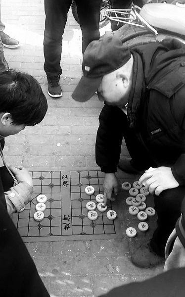在另一场棋局中,戴帽子的男子当摊主摆摊 摄/法制晚报记者 刘汨