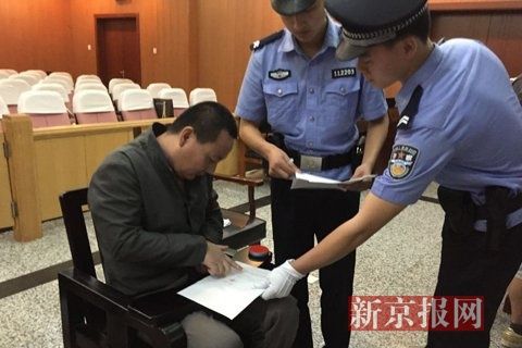 被告人田某,在法庭讯问结束后,在笔录上签字画押。新京报记者 尹亚飞 摄