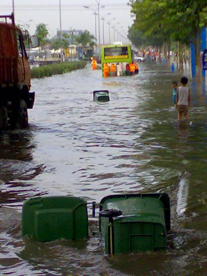 图文:垃圾桶漂浮在马路上的积水中