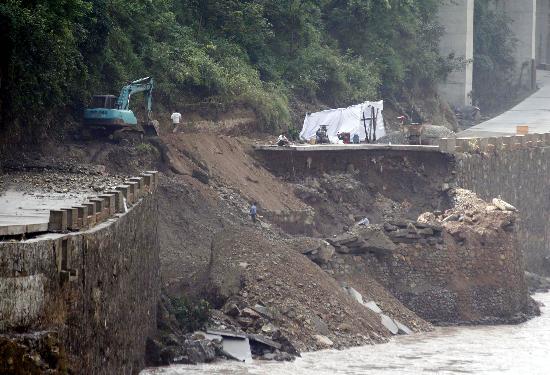 图文:施工人员清理被洪水冲垮的道路