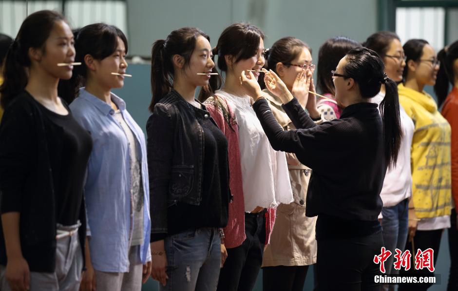 南京青奥会礼仪志愿者口含筷子练笑容 -- 佛山