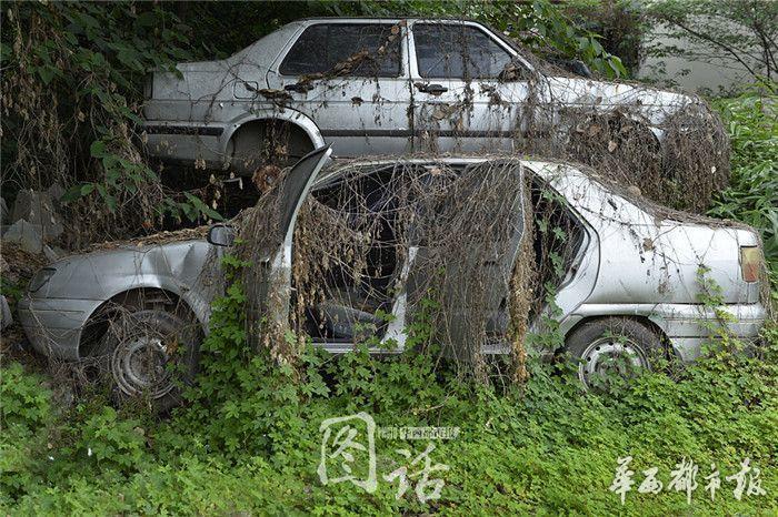 成都一心桥街一停车场的角落,上百辆报废汽车及摩托车,层层叠叠堆高清图片