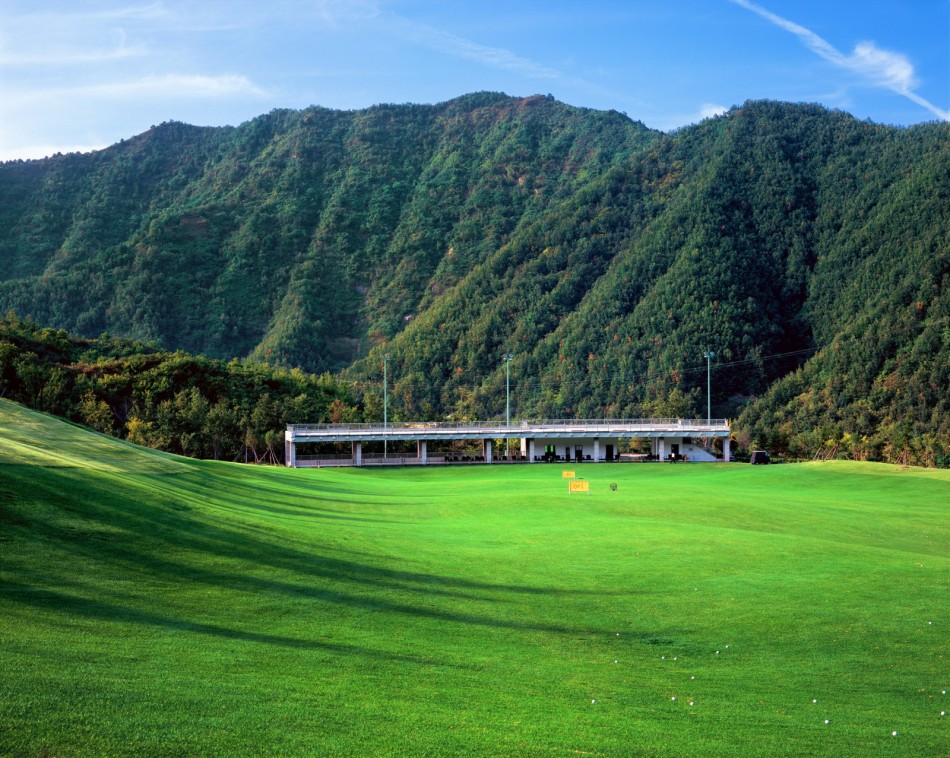 夕阳西下，酒店建筑披上金色外衣，静谧地坐落在球场与群山环抱之中