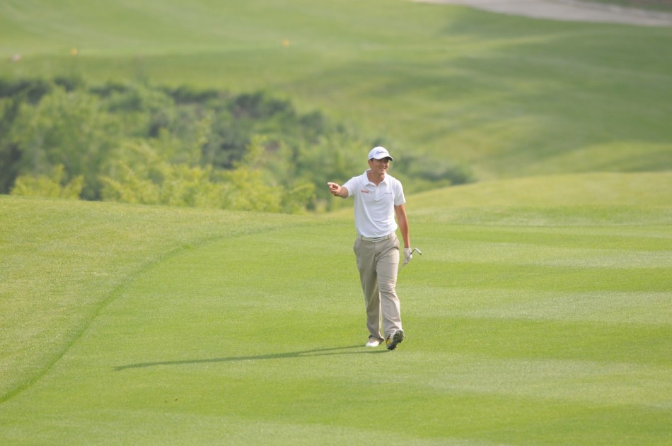 栾晓沛与外籍球童并肩站立，手指远方果岭，共同研判击球路线与策略