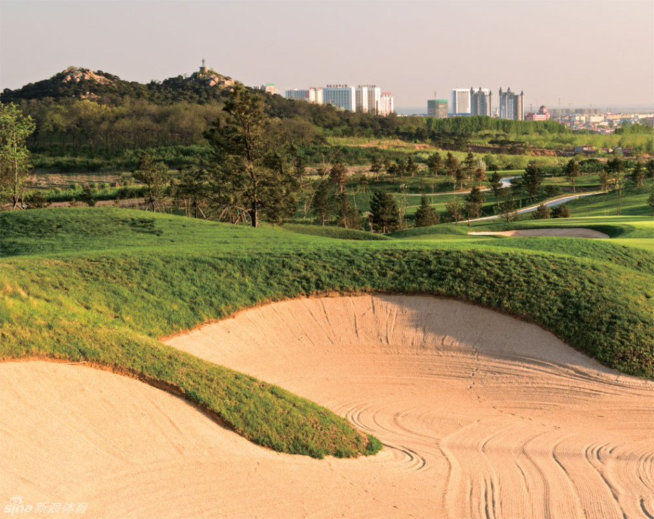 造型嶙峋的巨型岩石耸立于果岭一侧，与修剪整齐的翠绿果岭形成强烈对比，展现着自然之力与人工匠心的完美共存。