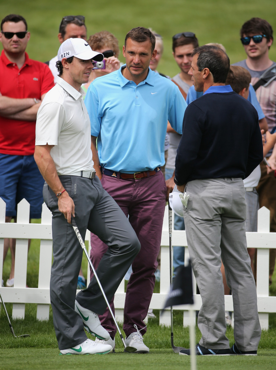 电视主持人杰里米·凯尔正微笑着轻拍罗里·麦克罗伊的肩膀，仿佛在宽慰这位高尔夫球星，场边观众报以会心的笑容。