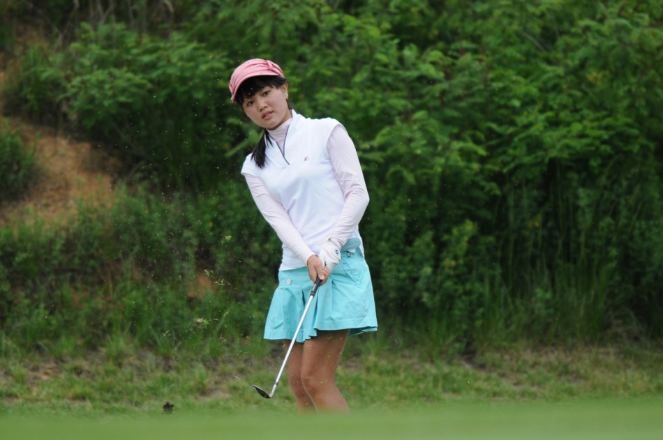 专注的推杆瞬间，球手沉稳俯身，目光如炬，锁定球洞方向