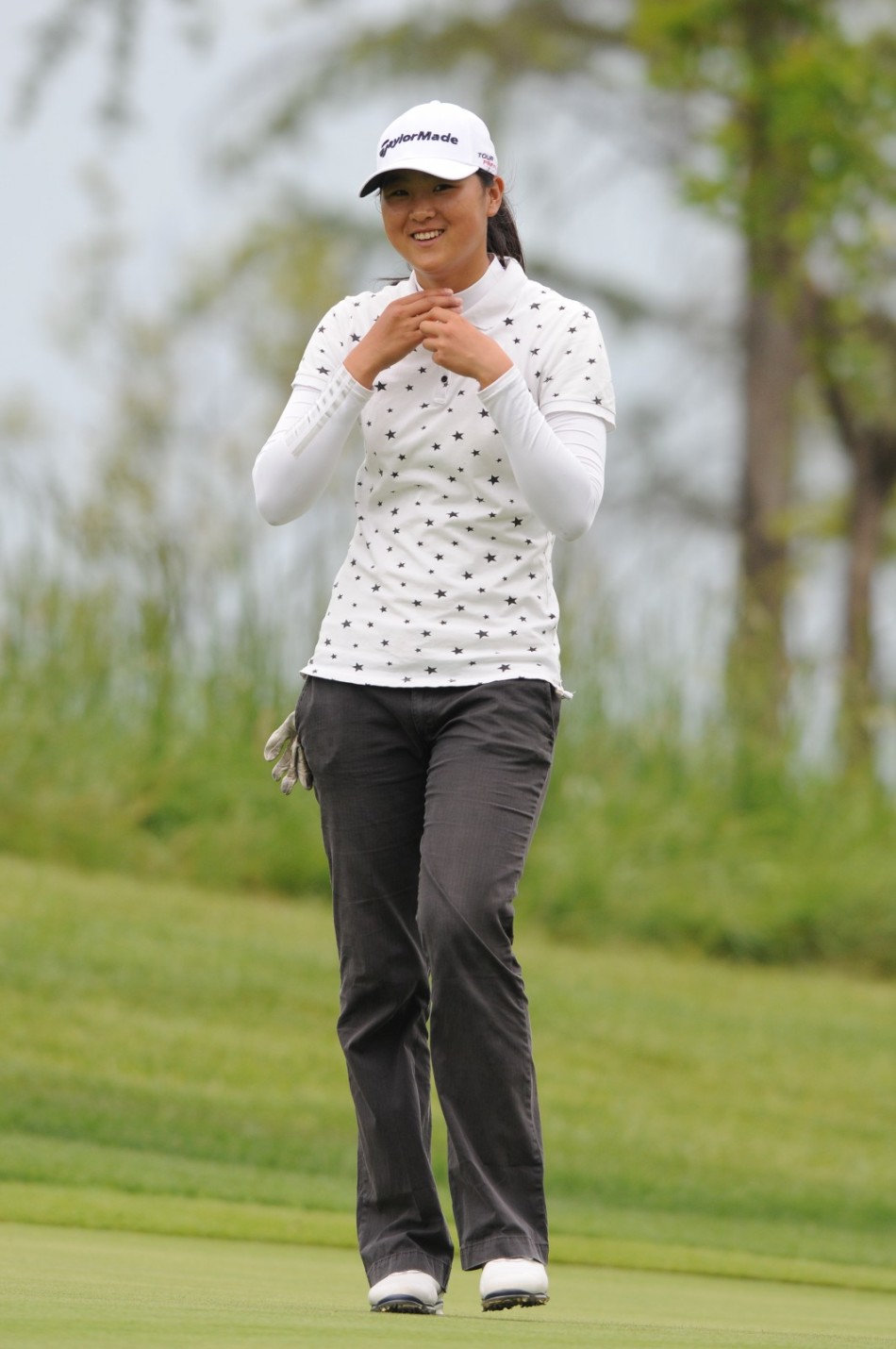 女球员在果岭上露出灿烂甜笑，眼中闪烁着成功推杆后的喜悦光芒