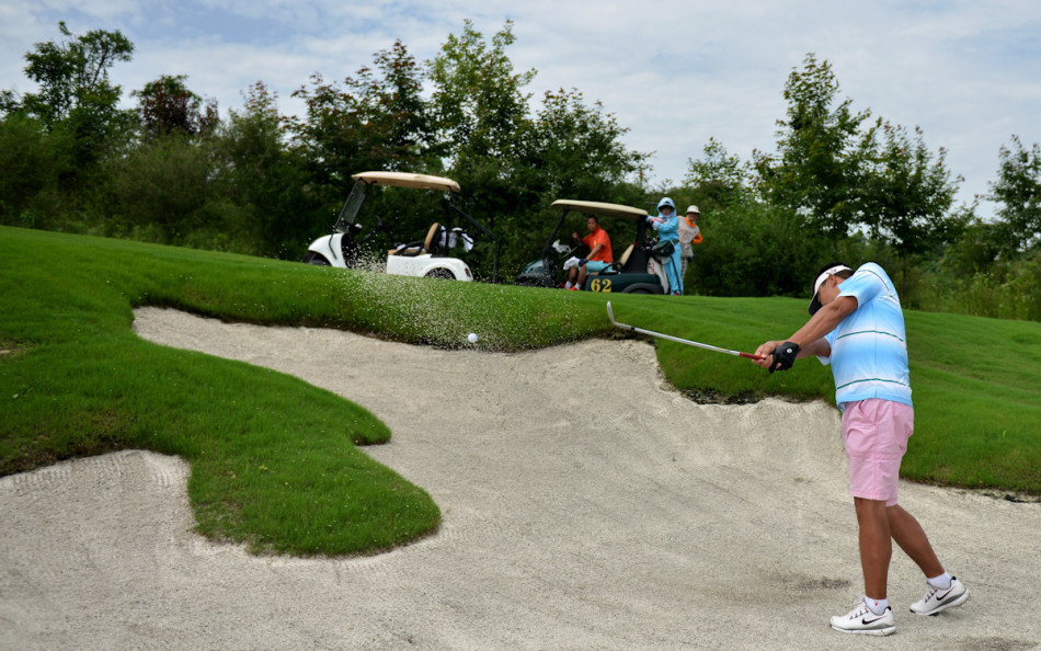选手在果岭边细心推杆,草纹在阳光下清晰可见,他屈膝俯身,眼神如炬,仿佛整个世界都凝聚在这颗即将滚向洞杯的小小白球上。