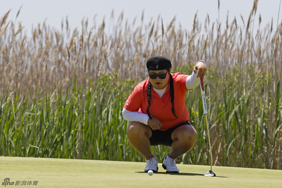 金楚笼在果岭边专注推杆，神情沉稳，计算着球的每一条滚动的路线。