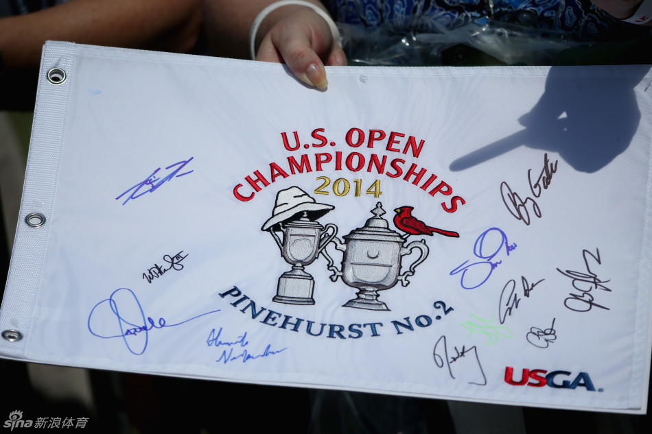 珍贵的赛场记忆：一位球迷正自豪地展示收集到球星签名的高尔夫果岭旗，脸上洋溢着幸福的笑容