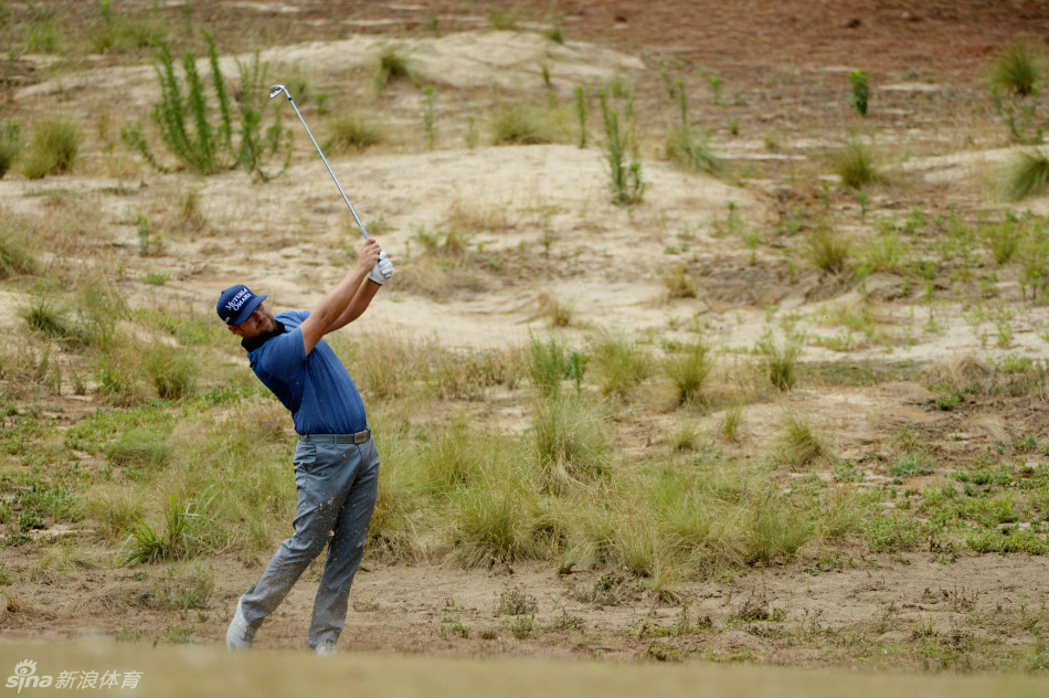 小白球深陷沙坑之中，背景是翠绿的果岭，构成一幅充满悬念与挑战的画面