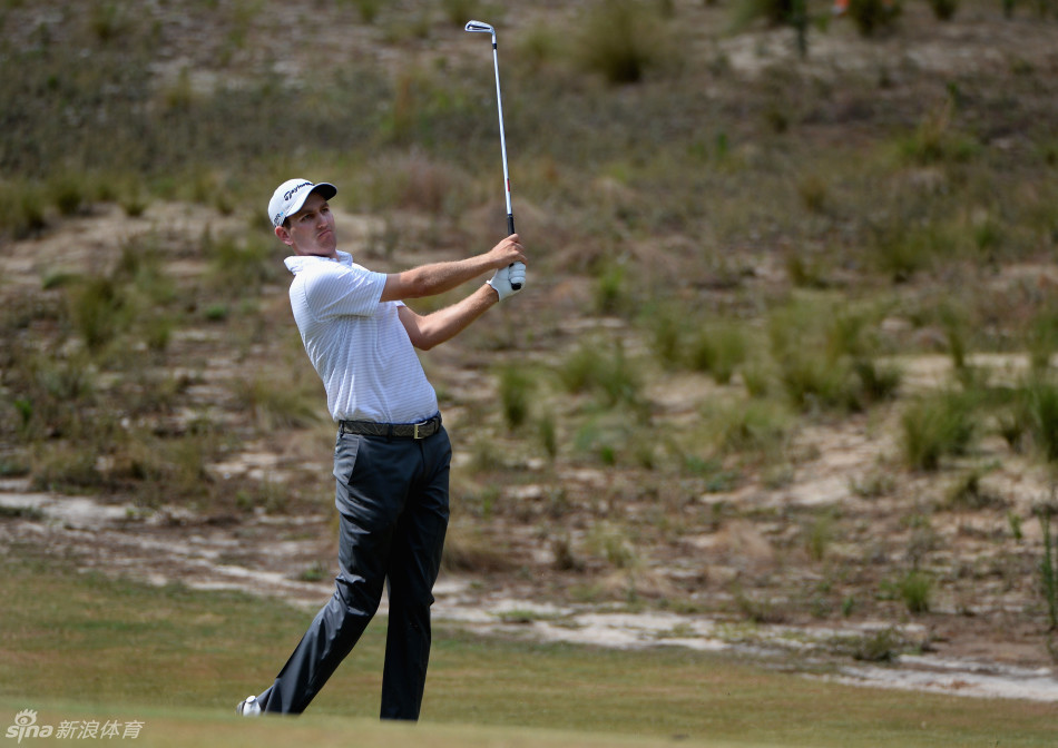 从低角度仰望，球手在沙坑中全力挥杆的瞬间，沙尘弥漫，动感十足