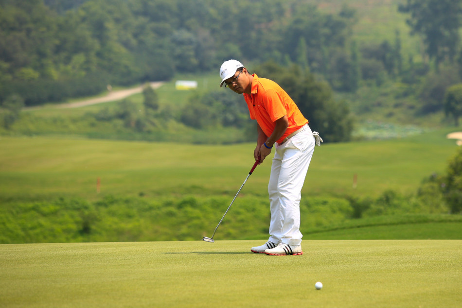 宝卓队队长朱三军于果岭上俯身凝视，沉稳推杆，决胜时刻的专注与冷静显露无遗。