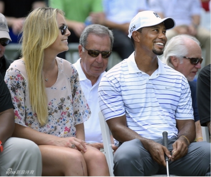 伍兹侧身指导同伴，眼神专注而友善，展现巨星在赛场之外耐心传授的温情一面