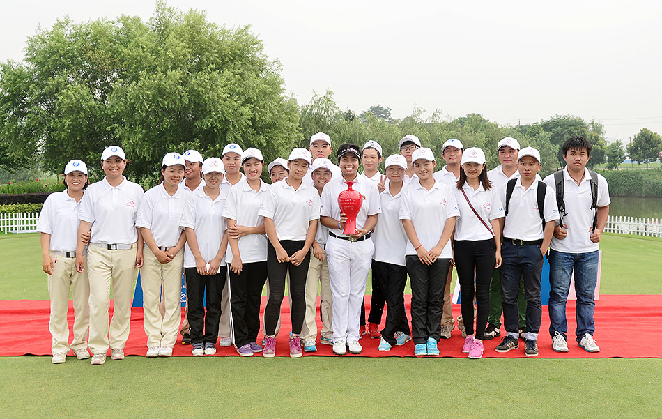 冠军帕瑞萨被热情的志愿者们簇拥在中央，大家脸上都挂着真挚的笑容，共同分享赛事成功的喜悦。