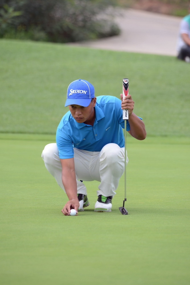 职业球员邢建福在果岭边屈身,以专业而深邃的目光研读球路走向与草纹脉络。