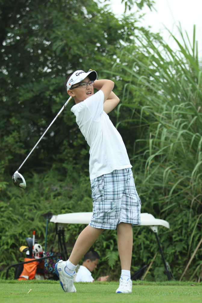 年轻选手赵泳画正专注地进行推杆，阳光洒在他稚嫩而认真的脸庞上，球杆与小白球形成优美的构图。