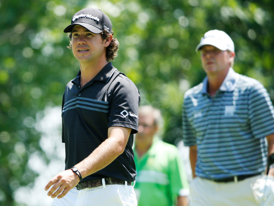 哈曼在果岭上全神贯注地俯身阅读推杆线路，表情严肃而认真，决胜时刻的专注力显露无遗