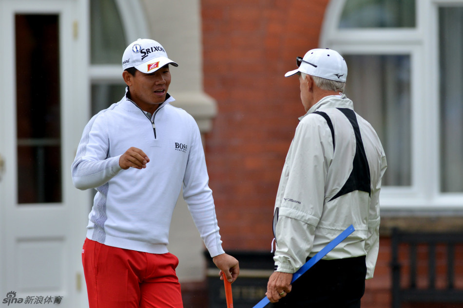 吴阿顺与教练乔·蒂尔在练习果岭旁专注交流，教练正用手势强调推杆时手腕角度的保持。