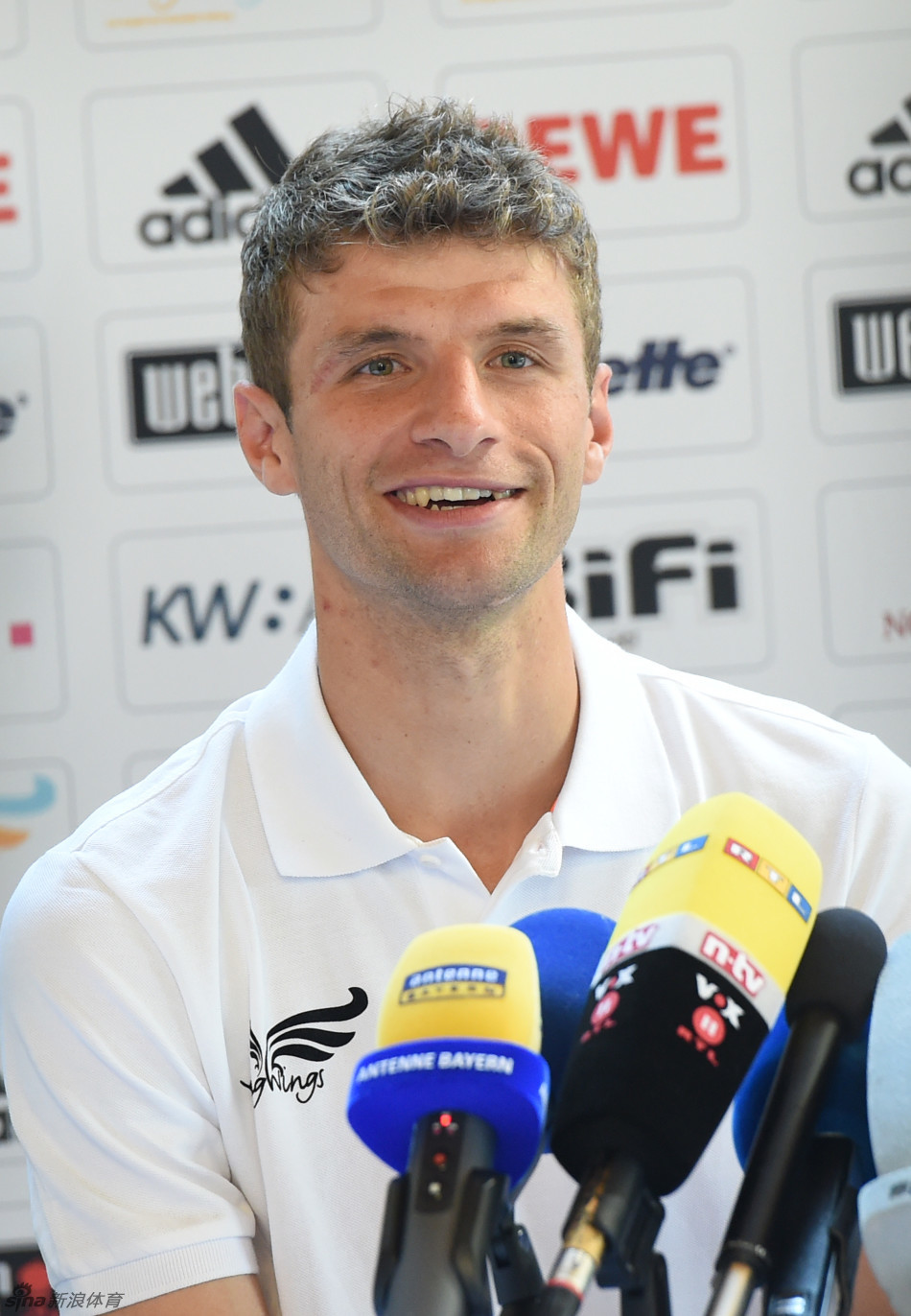 穆勒与一位为球员背包的工作人员并肩而行，展现球队大家庭的温暖氛围。