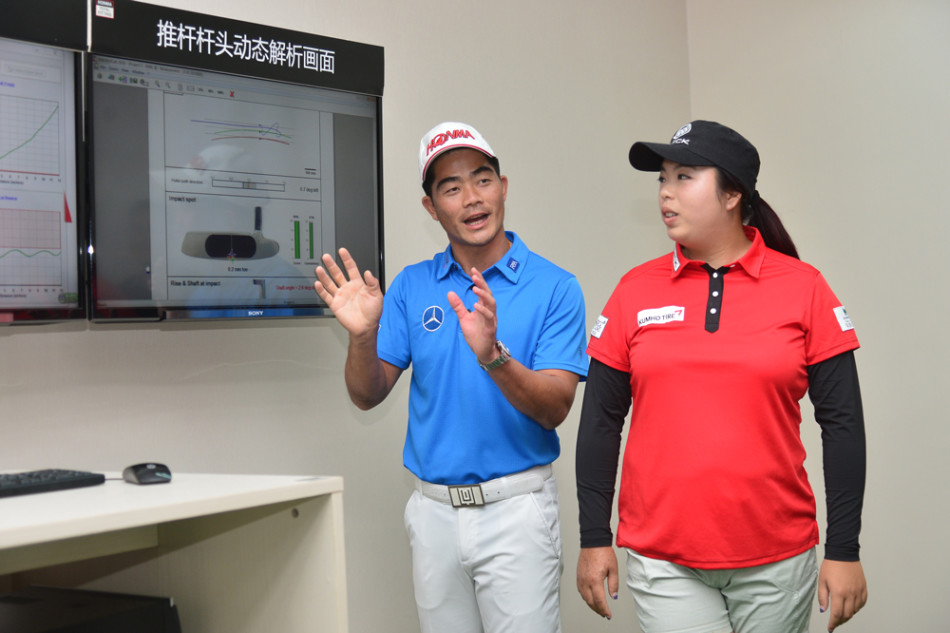 梁文冲俯身专注地为一位小朋友调整推杆姿势，神情温和而耐心