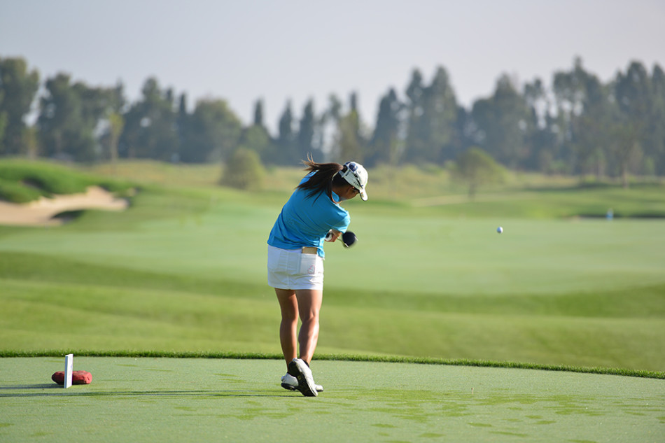 轻盈步伐：一位女球手背着球包走向下一洞，她的背影在晨光中显得轻盈而坚定，充满了专注与优雅。