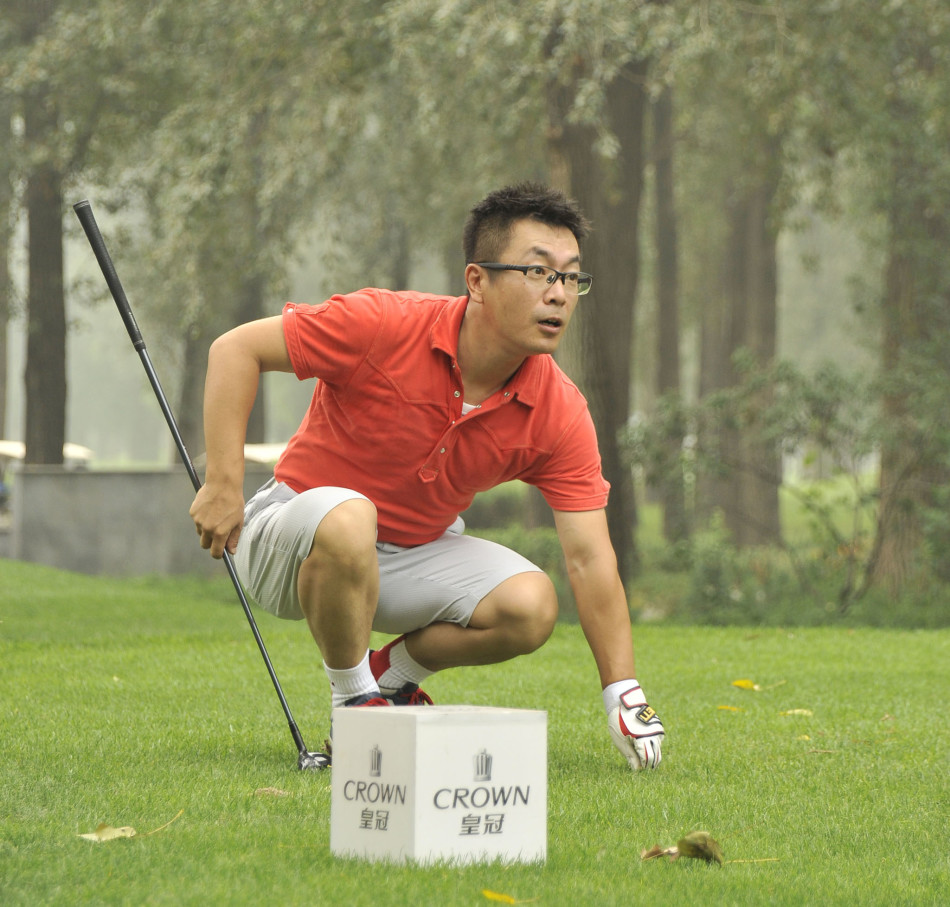 一位高尔夫选手正全神贯注地挥动一号木，白色小球在空中划出优雅的抛物线，背景是辽阔的蓝天与绵延的球道。