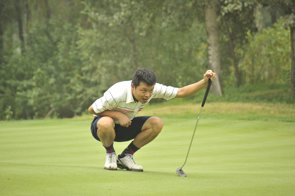 冠军韩良手持奖杯，面带微笑接受媒体采访，身后是围观的观众与飘扬的赛事旗帜，胜利的喜悦洋溢在绿茵场上。