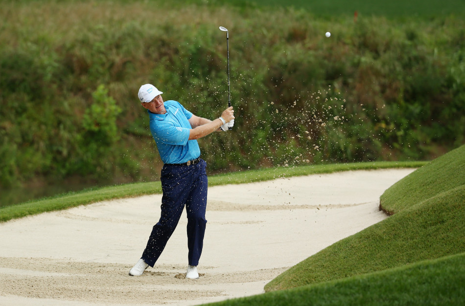 厄尔斯在沙坑中救球，沙砾飞扬瞬间，他神情专注，巧妙利用杆面角度将球轻柔地托起，困境中展现大师级的处理技巧。