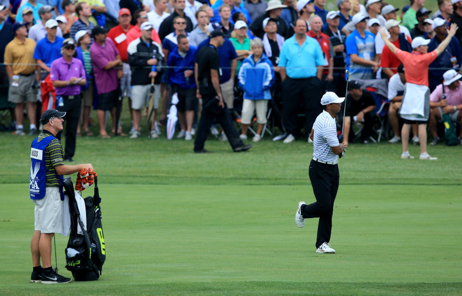 阳光下，伍兹独自走在球道上，微微低头沉思，身后的背包见证着他职业生涯的起伏与重量。