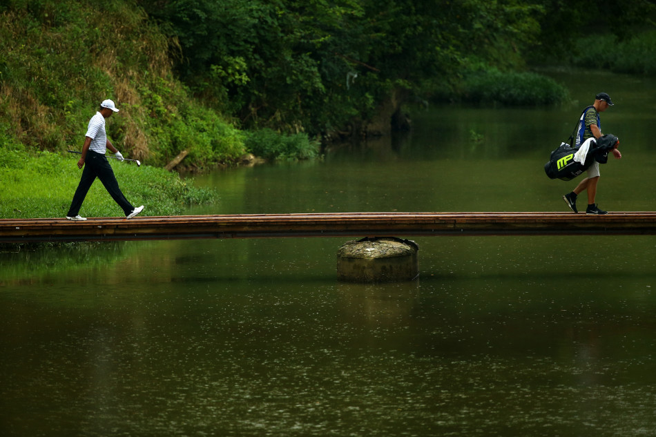 一轮比赛结束，伍兹背对镜头走向场边，他的身影在广阔的球场背景下显得孤独却坚定，仿佛承载着一部属于自己的高尔夫史诗。