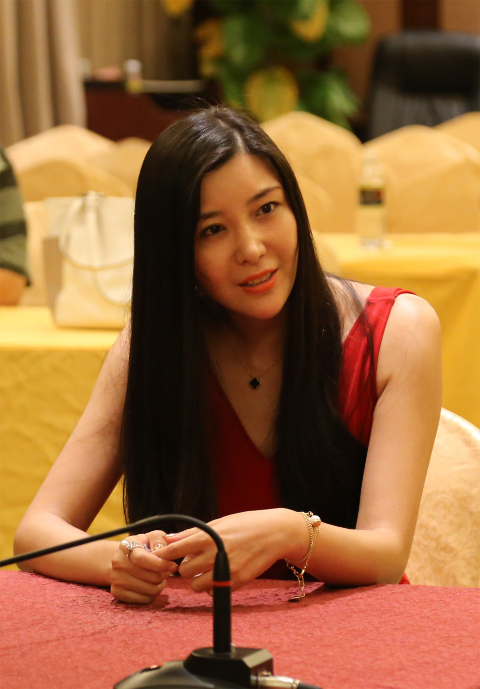 身着优雅礼服的佳丽Cici手持号码牌，眼神专注地确认自己的数字，周围光影衬托出她沉静而自信的神情。