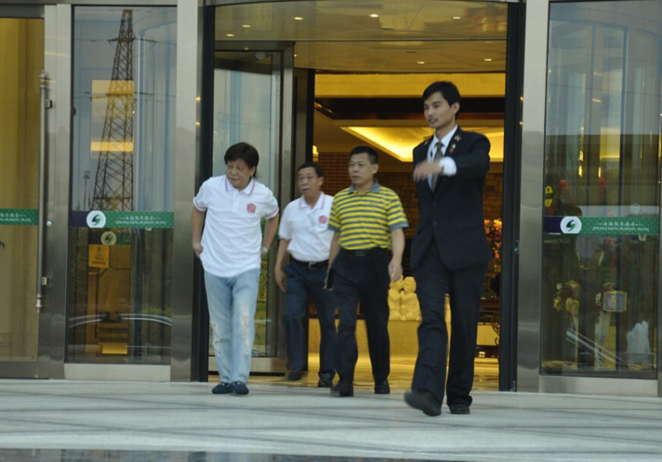 梁小龙与工作人员在球场边亲切合影,笑容爽朗如江湖故人