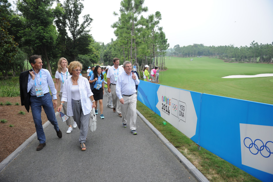 自拍的欢乐瞬间：国际奥委会主席巴赫先生与一位年轻的志愿者女孩面带灿烂笑容，头挨着头正在开心自拍，背景是其他志愿者羡慕与欢快的目光。