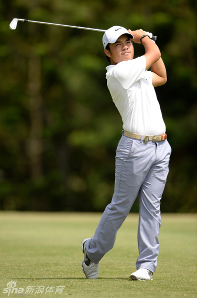 菲律宾小将塔布埃纳神情专注，在果岭边仔细审视推杆线路，阳光洒在他年轻的脸上，充满希望。