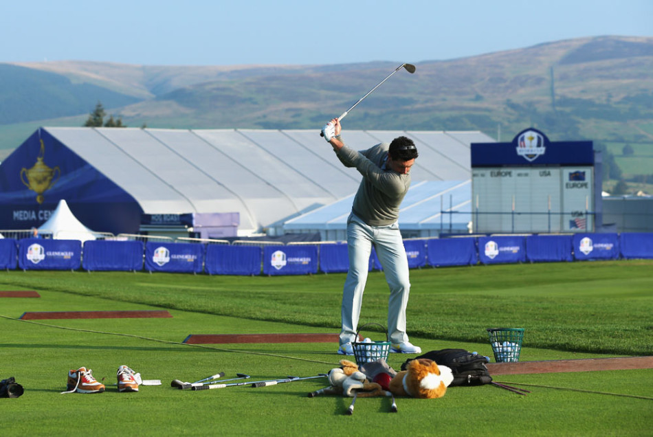 麦克罗伊在空荡的练习果岭上凝神推杆，身影被晨光拉长，大战前的宁静中弥漫着专注的力量。