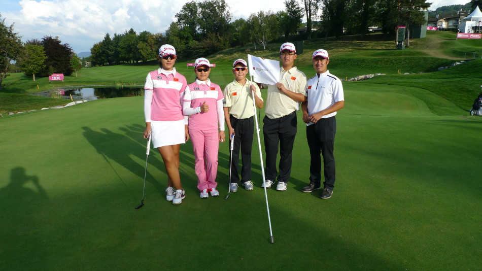 四位年轻的中国高尔夫选手在依云锦标赛标志前并肩而立，笑容灿烂如阿尔卑斯山的阳光，展现出无限的活力与默契。