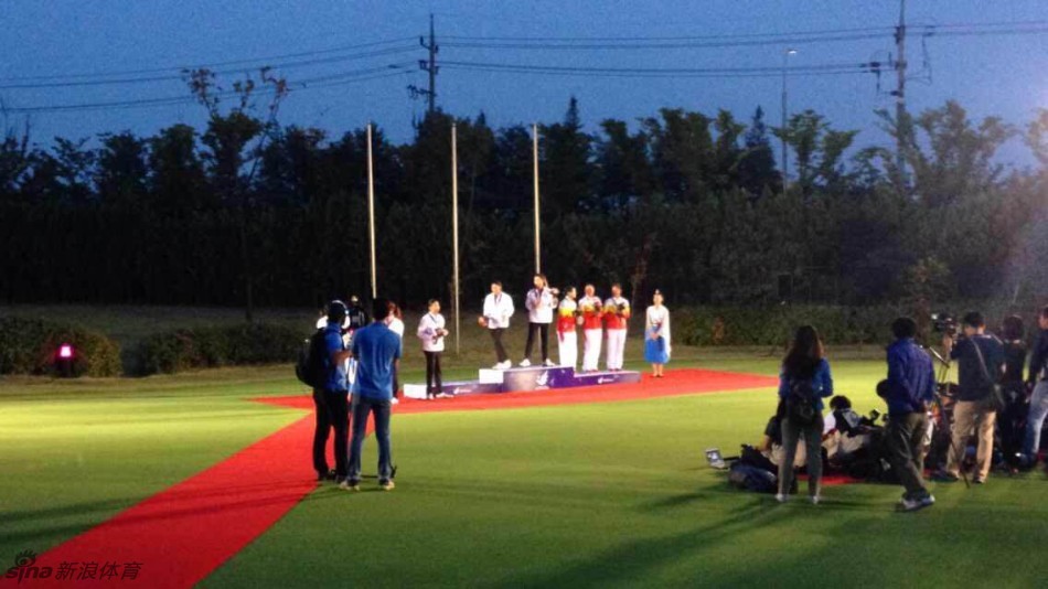 颁奖仪式上,中国女子高尔夫球队的三位姑娘站在季军领奖台上,一同举起手中的铜牌向观众致意。